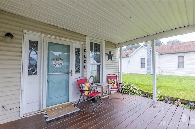 wooden deck featuring a porch and a lawn