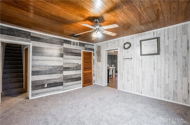 empty room with ceiling fan, wooden walls, carpet floors, and wooden ceiling