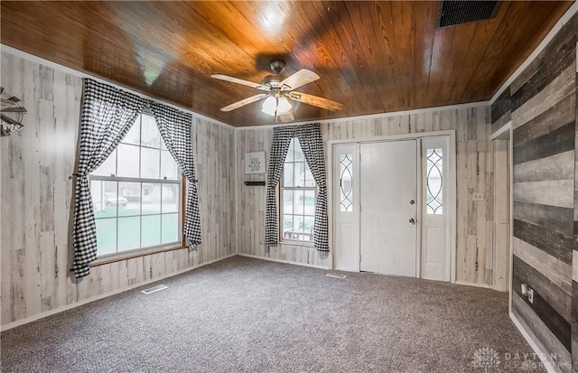 carpeted entryway with ceiling fan, wood walls, and wooden ceiling