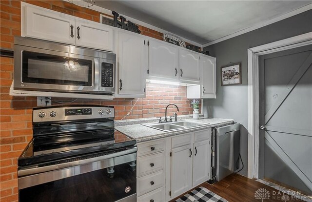 kitchen featuring appliances with stainless steel finishes, dark wood-type flooring, crown molding, sink, and white cabinets