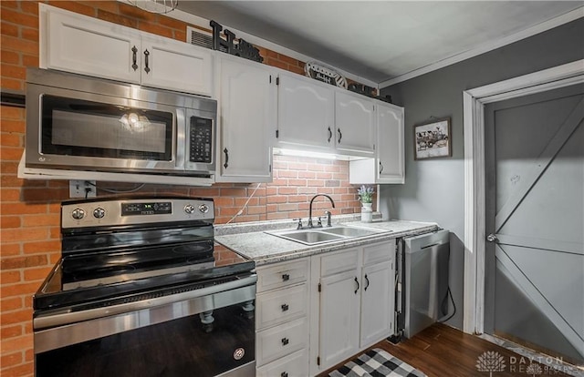 kitchen featuring sink, appliances with stainless steel finishes, white cabinetry, tasteful backsplash, and dark hardwood / wood-style flooring