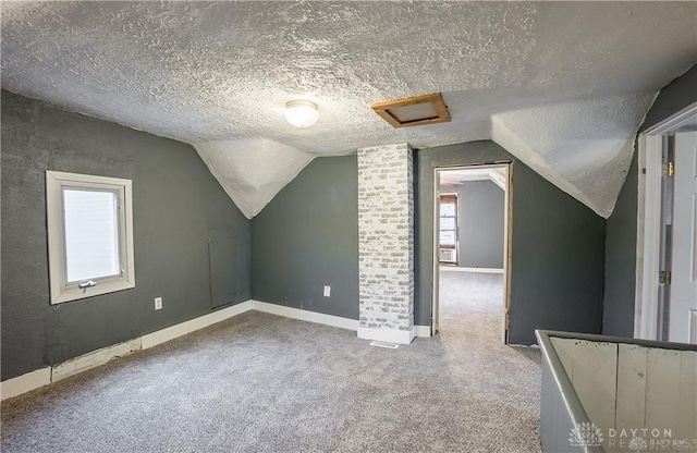 bonus room with vaulted ceiling, carpet, and a textured ceiling