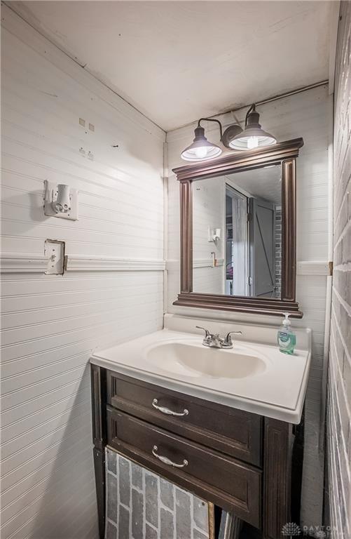 bathroom featuring vanity and wood walls