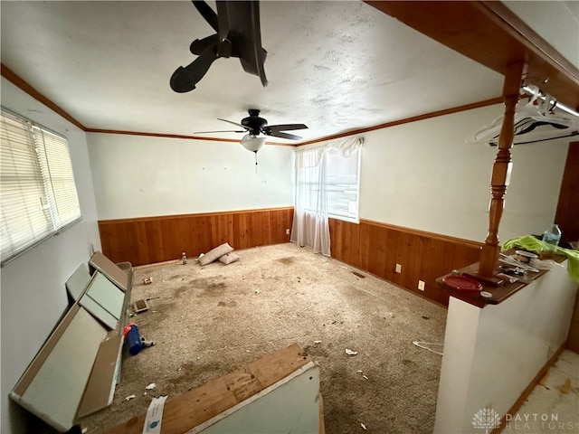 miscellaneous room featuring carpet, ceiling fan, ornamental molding, and wooden walls