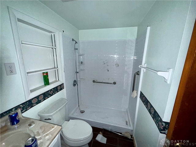 bathroom featuring tile patterned flooring, vanity, toilet, and tiled shower