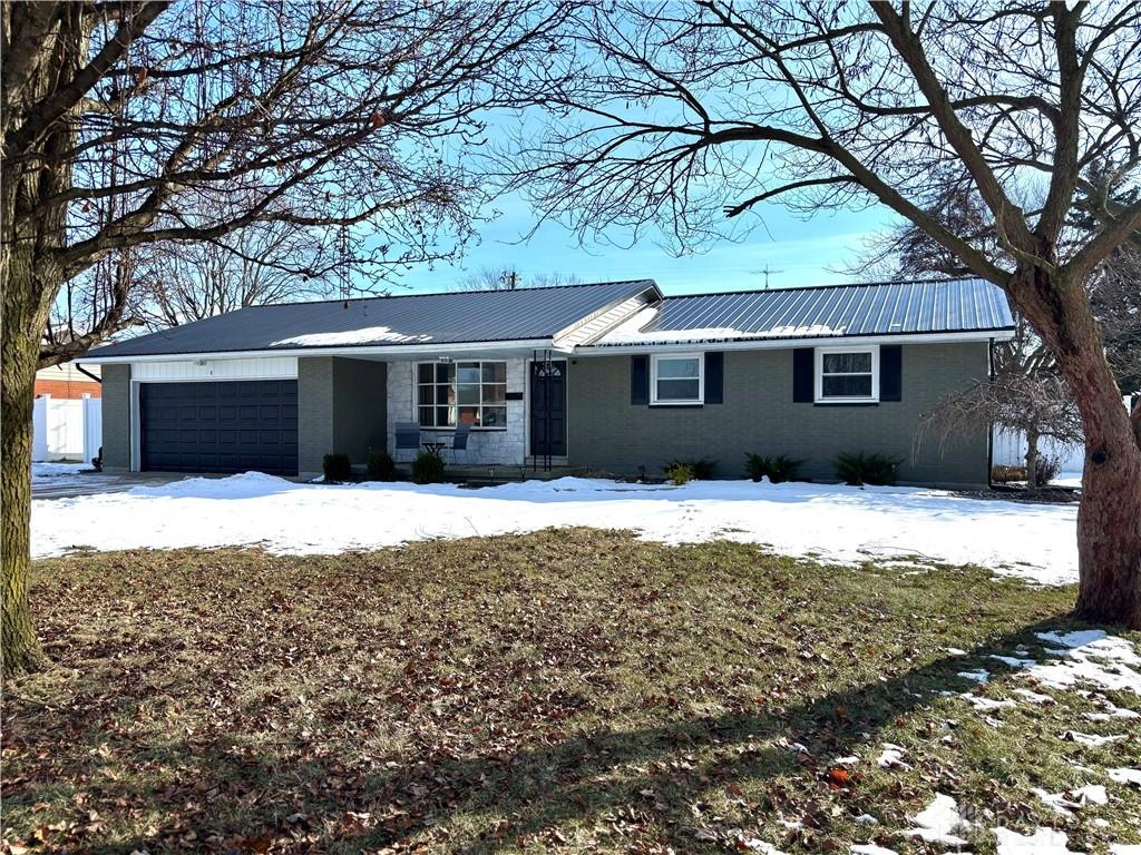 ranch-style home featuring a garage, metal roof, and brick siding