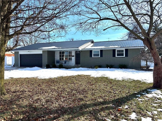 ranch-style home featuring a garage, metal roof, and brick siding