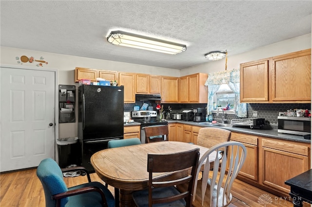 kitchen with appliances with stainless steel finishes, light wood-type flooring, backsplash, a textured ceiling, and sink