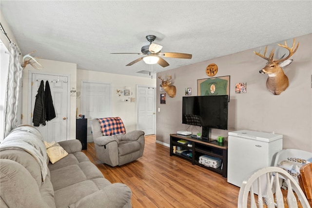 living room with ceiling fan, light hardwood / wood-style floors, and a textured ceiling