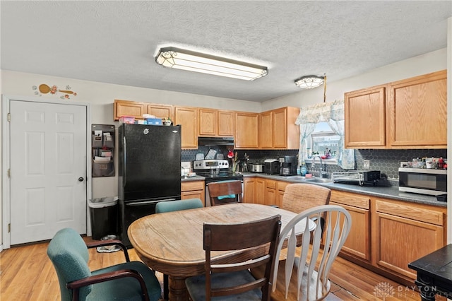 kitchen featuring appliances with stainless steel finishes, backsplash, a textured ceiling, sink, and light hardwood / wood-style flooring