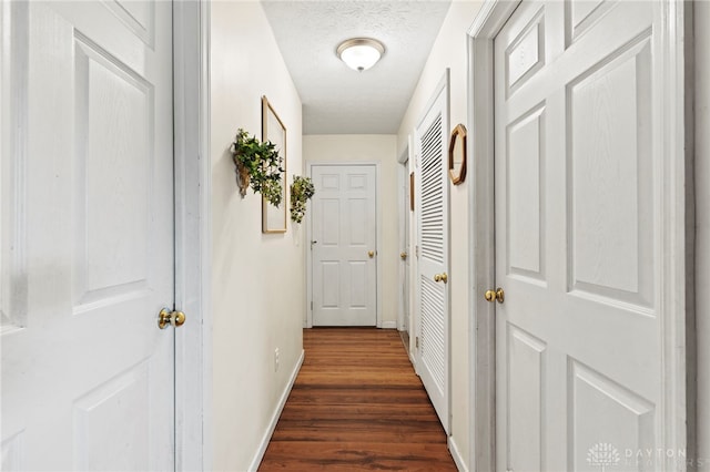 hallway with a textured ceiling and dark wood-type flooring