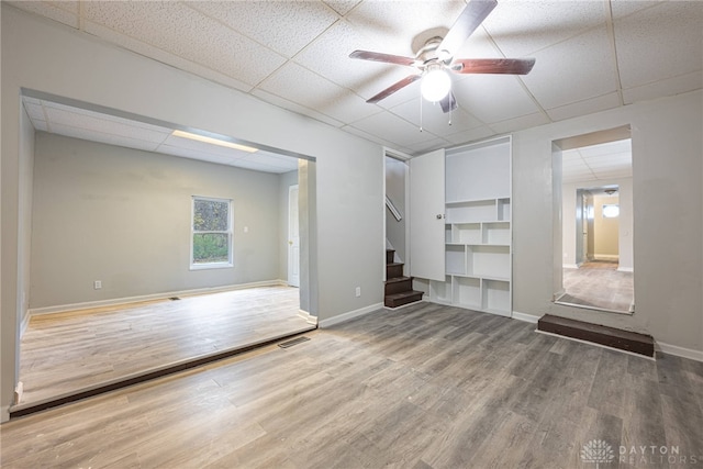 interior space with a paneled ceiling, ceiling fan, and wood-type flooring