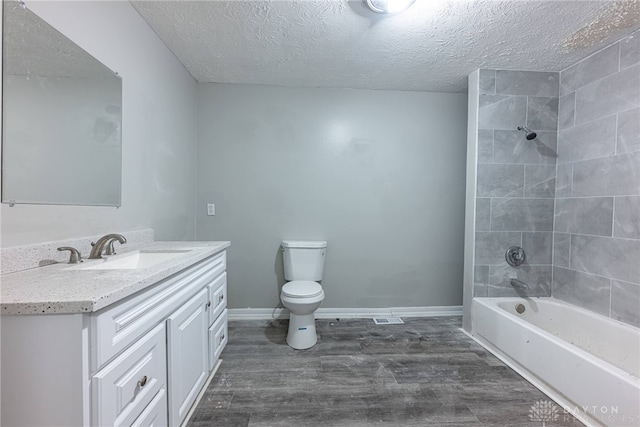 full bathroom featuring vanity, toilet, a textured ceiling, and tiled shower / bath