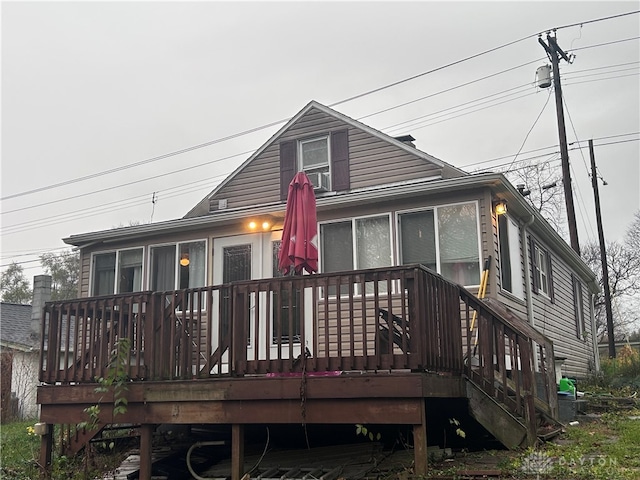 back of property with a wooden deck and a sunroom