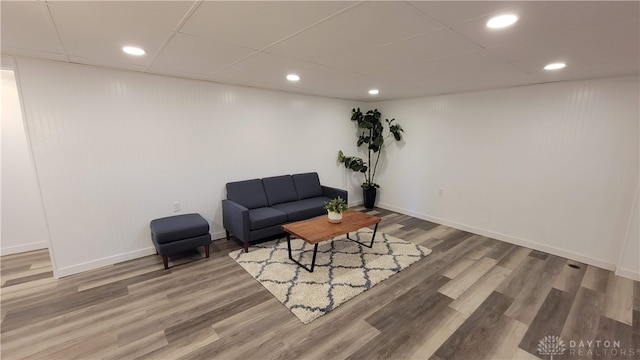 living room with hardwood / wood-style floors and a drop ceiling