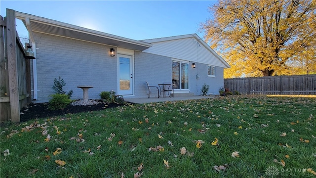 rear view of property featuring a lawn and a patio area