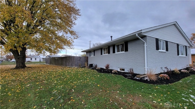 view of side of property featuring a lawn and central AC