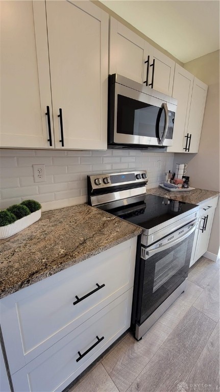 kitchen with white cabinetry, backsplash, stone counters, and appliances with stainless steel finishes