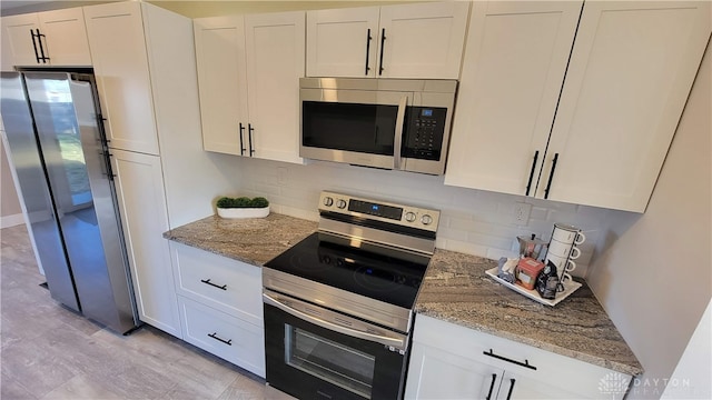 kitchen featuring light stone counters, white cabinetry, stainless steel appliances, and tasteful backsplash