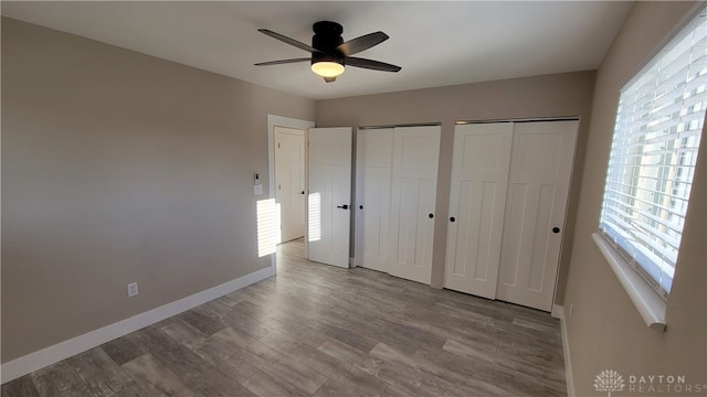 unfurnished bedroom featuring ceiling fan, two closets, and light wood-type flooring