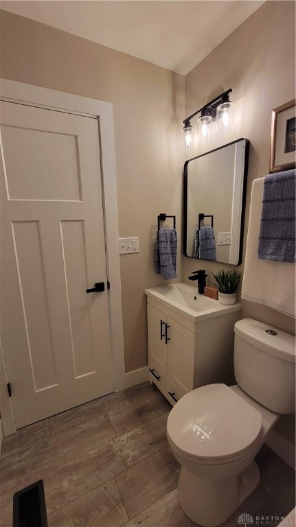 bathroom with hardwood / wood-style floors, vanity, and toilet