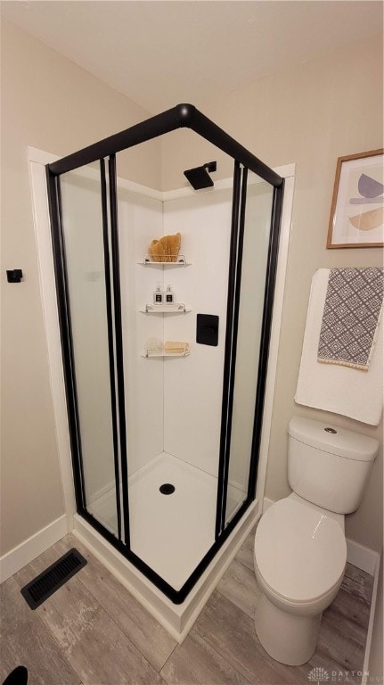 bathroom with hardwood / wood-style flooring, toilet, and an enclosed shower