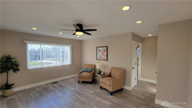 living area featuring hardwood / wood-style floors and ceiling fan