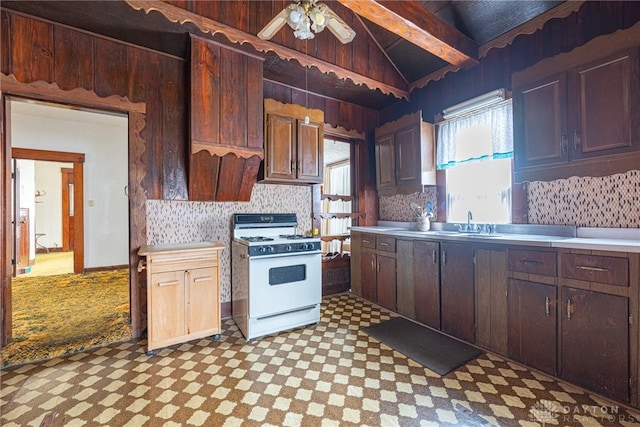 kitchen featuring backsplash, lofted ceiling with beams, ceiling fan, dark brown cabinets, and white range with gas stovetop