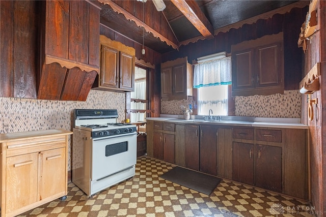 kitchen featuring backsplash, white range with gas cooktop, sink, and vaulted ceiling with beams