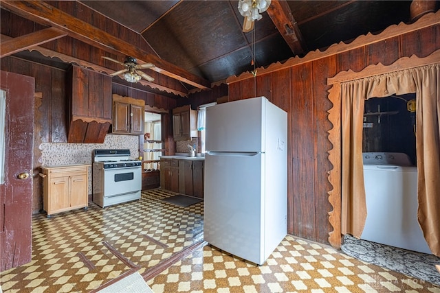 kitchen with lofted ceiling, washer / dryer, white appliances, and wooden walls