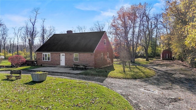 view of side of property with a yard, a patio, and a storage shed