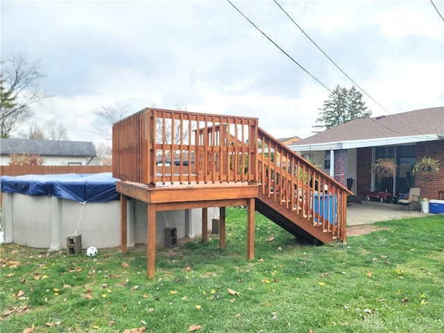 wooden deck featuring a lawn, a patio area, and a covered pool