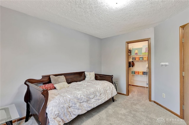 carpeted bedroom with a spacious closet and a textured ceiling