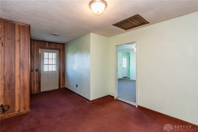 empty room with wood walls and dark carpet