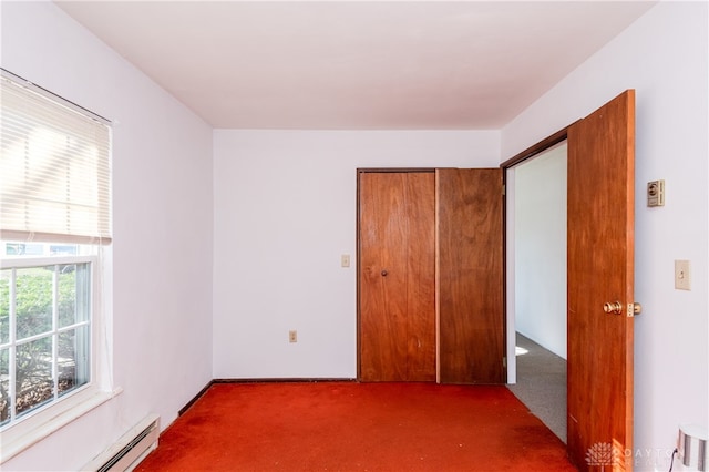 interior space featuring dark carpet, baseboard heating, and a closet