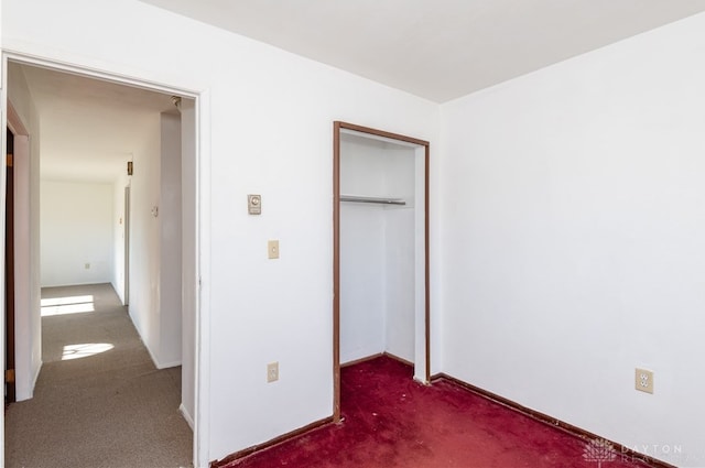 unfurnished bedroom with dark colored carpet and a closet