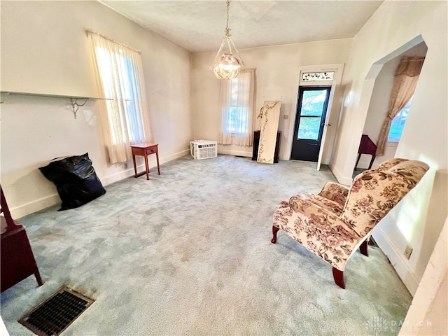 sitting room with a wall mounted AC, carpet, and an inviting chandelier