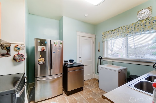 kitchen with stove, white cabinets, refrigerator, sink, and stainless steel refrigerator