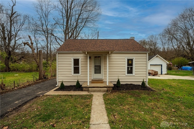 bungalow with an outbuilding, a front lawn, and a garage