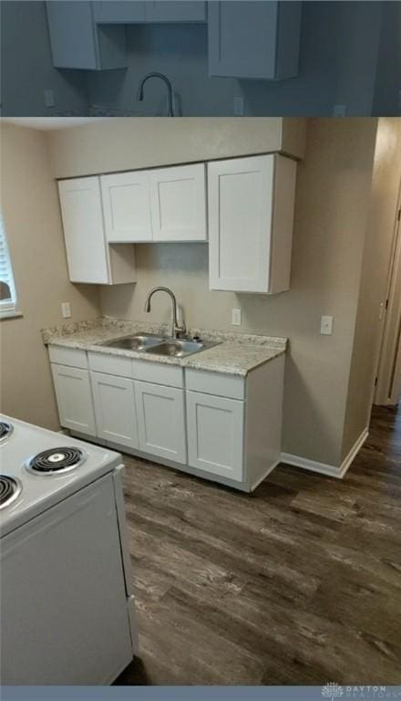 kitchen with light countertops, white range with electric cooktop, a sink, and white cabinetry