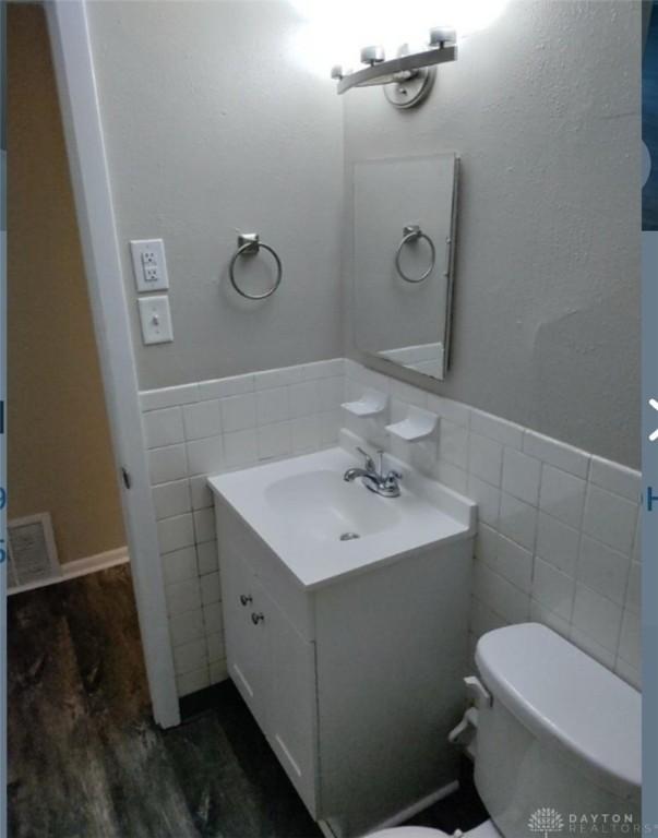 bathroom with hardwood / wood-style floors, vanity, toilet, and tile walls