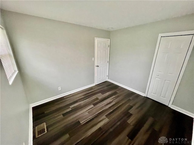 unfurnished bedroom with dark hardwood / wood-style floors and a closet