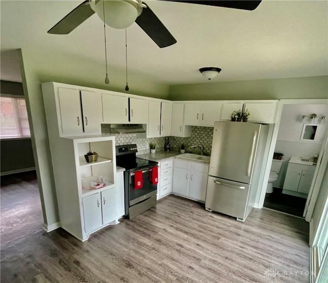 kitchen with white cabinetry, sink, light hardwood / wood-style flooring, range with electric stovetop, and stainless steel fridge