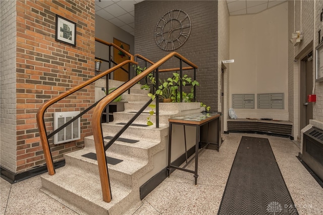 stairway with a towering ceiling and brick wall