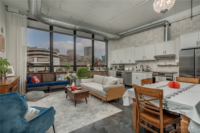 interior space featuring white cabinetry, sink, stainless steel appliances, a high ceiling, and decorative backsplash