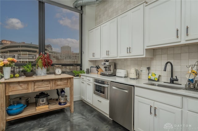 kitchen featuring decorative backsplash, white cabinetry, sink, and stainless steel appliances