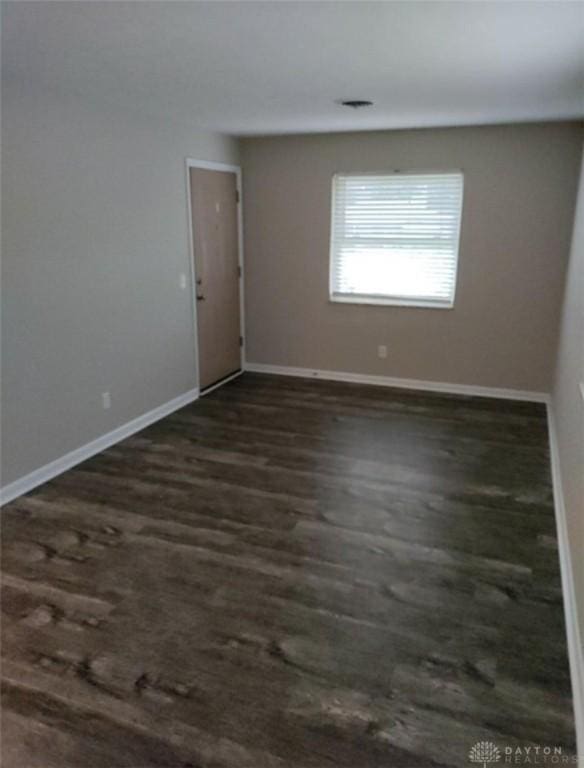 empty room with dark wood-type flooring and baseboards