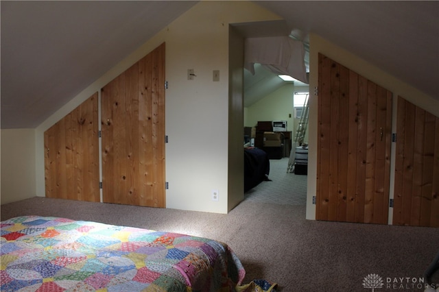 bedroom with lofted ceiling, carpet floors, and wooden walls