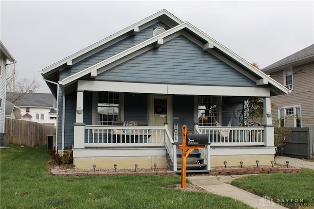 bungalow-style house featuring a porch, central air condition unit, and a front yard