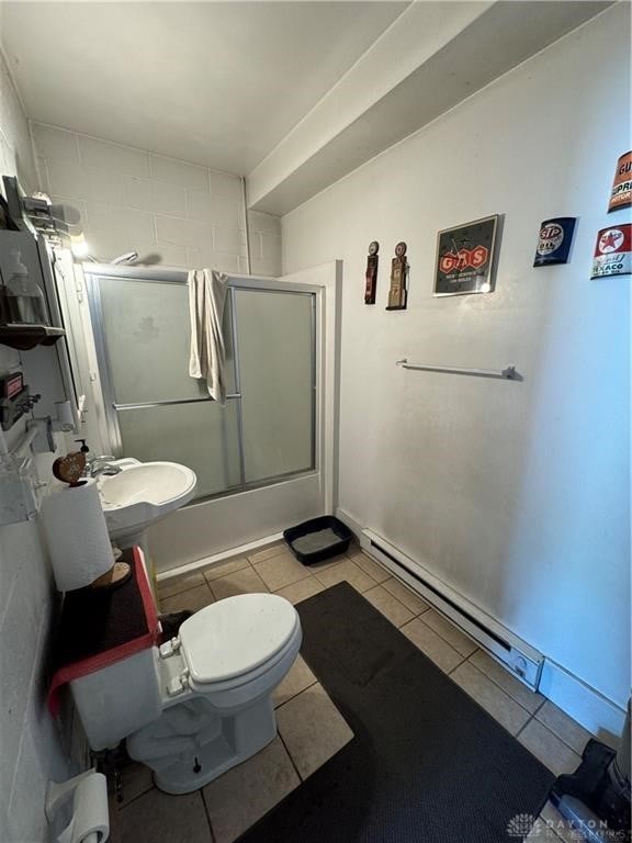 bathroom with tile patterned flooring, toilet, combined bath / shower with glass door, and a baseboard radiator